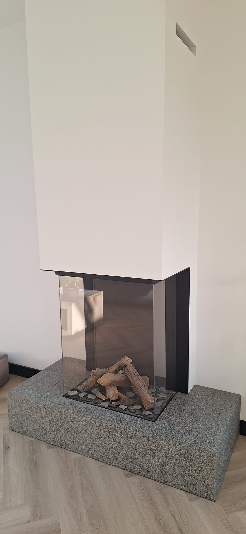 Driezijdige glazen haard als centraal punt in woonkamer